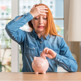 a woman looking tensed and putting a coin in her piggybank