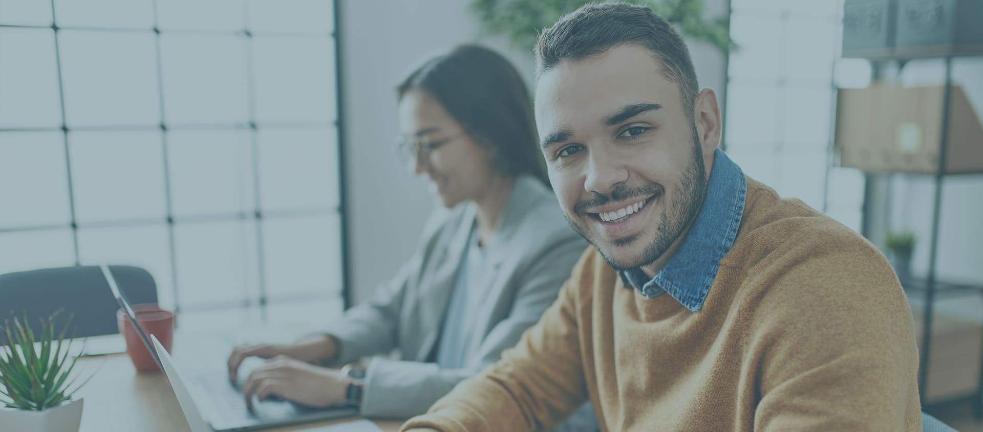 smiling male and female employees working on a laptop