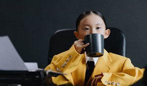 young boy drinking coffee in business suit